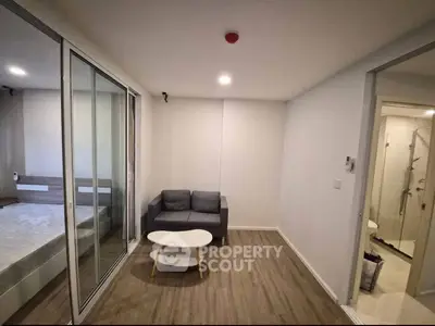 Modern living room with cozy sofa and sliding glass doors leading to bedroom.