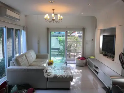 Bright and modern living room with large windows and garden view, featuring a cozy white sofa and sleek entertainment unit.