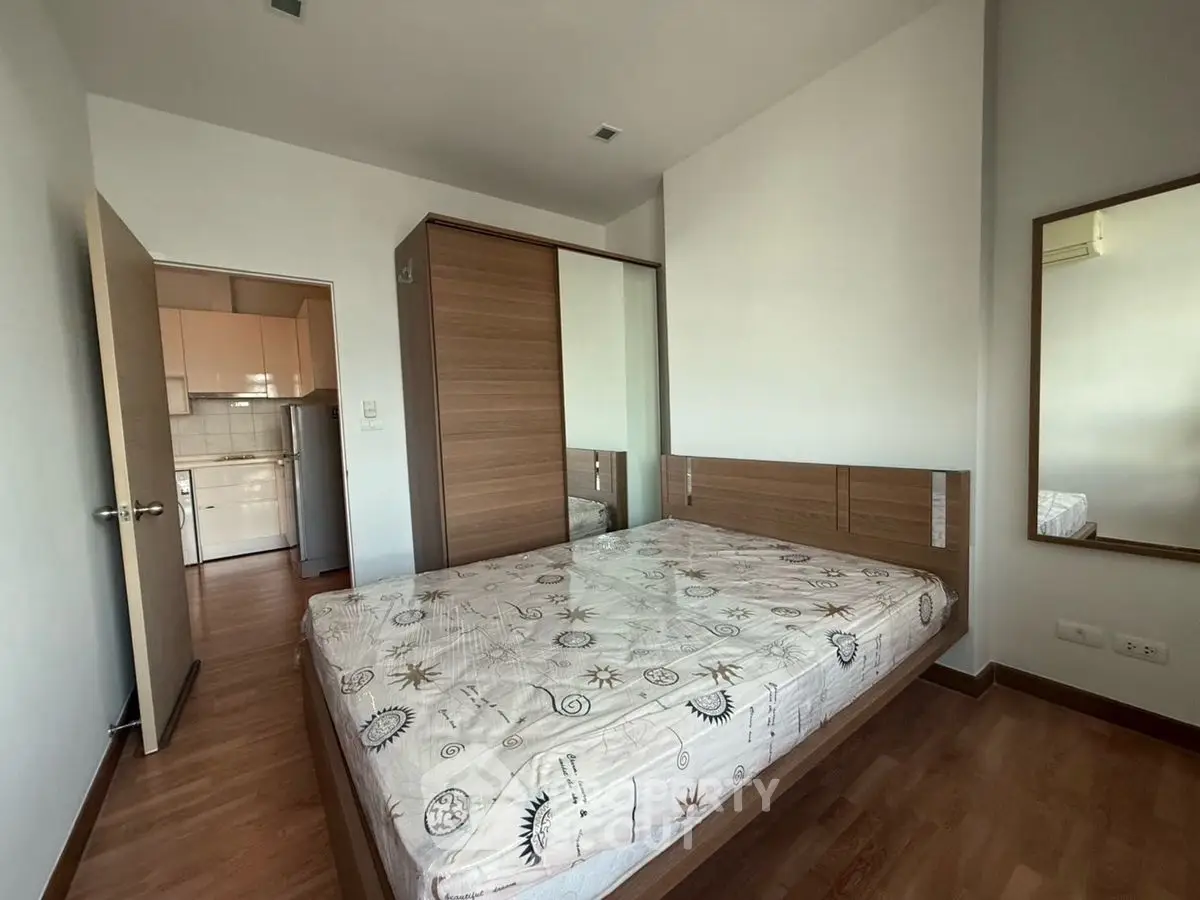 Cozy bedroom with wooden flooring and built-in wardrobe in modern apartment.