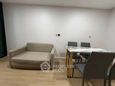 Modern living room with cozy sofa and elegant dining table set on wooden flooring.