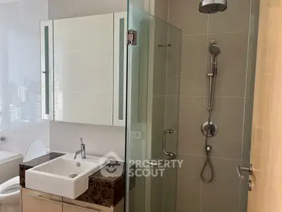 Modern bathroom with glass shower and sleek vanity in luxury apartment.