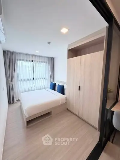 Modern bedroom with large window and stylish wardrobe in a bright apartment.