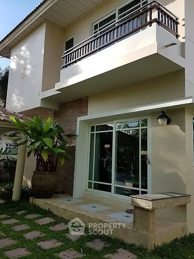 Charming two-story house with balcony and lush garden view