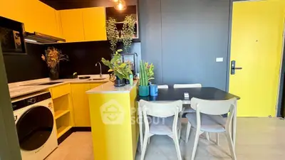 Modern kitchen with vibrant yellow cabinets and dining area, featuring sleek appliances and stylish decor.