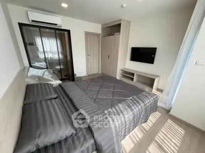 Modern bedroom with sleek design, featuring a comfortable bed, wall-mounted TV, and ample natural light.