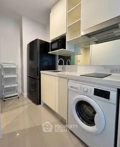 Modern kitchen with sleek appliances and washing machine in a compact layout.