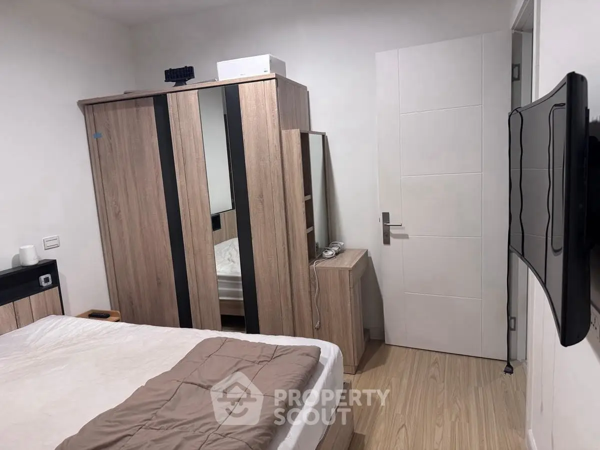 Modern bedroom with sleek wooden furniture and wall-mounted TV, perfect for cozy living.