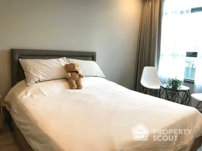 Cozy bedroom with plush bedding and natural light, featuring a charming teddy bear on the bed.