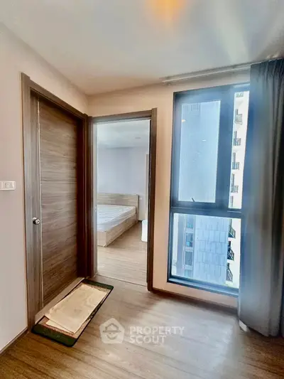 Modern bedroom with large window and wooden flooring in a stylish apartment.