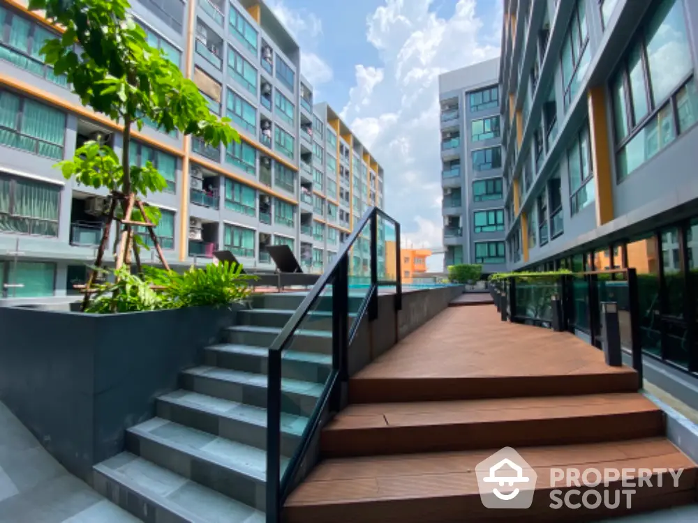 Modern apartment complex with outdoor seating and lush greenery