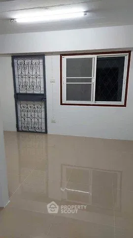 Spacious room with tiled flooring and secure window bars, ideal for versatile use.