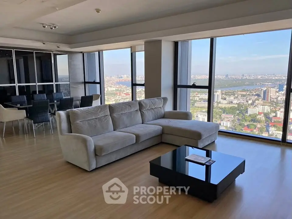 Spacious living room with panoramic city view and modern furnishings in high-rise apartment.