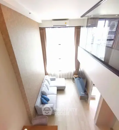Spacious modern living room with high ceiling and large windows in a stylish apartment.