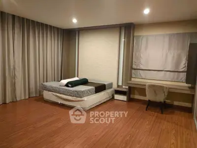 Spacious bedroom with modern decor and wooden flooring, featuring a comfortable bed and study area.