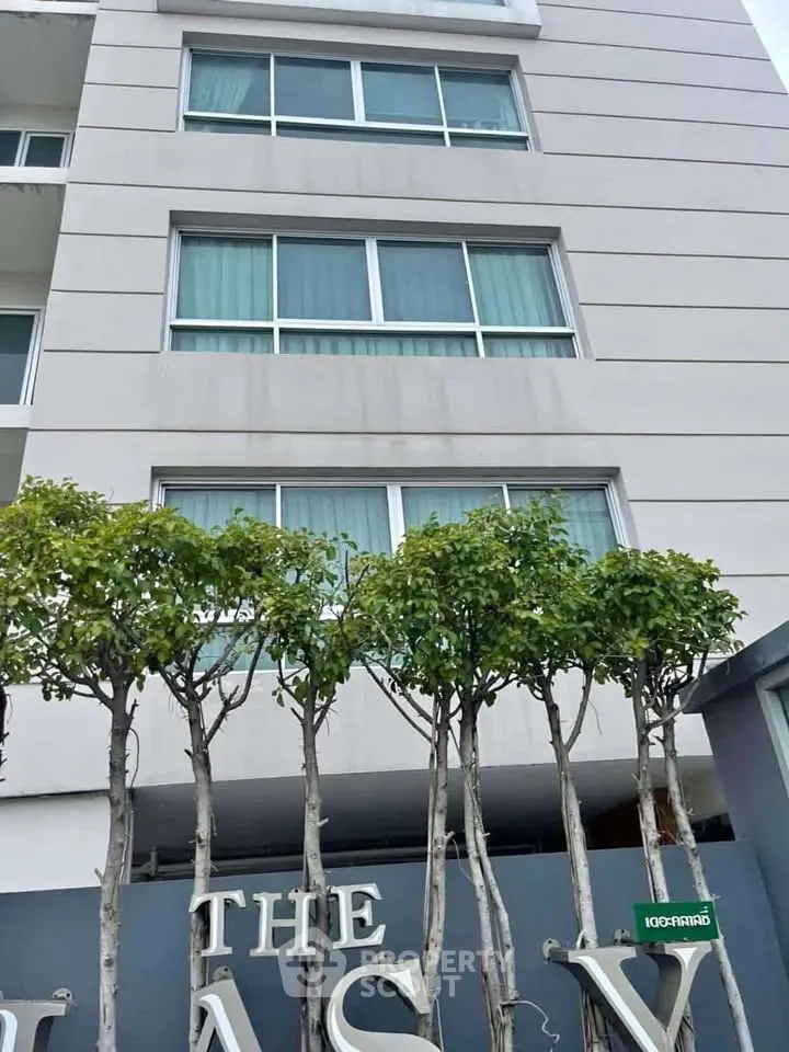 Modern apartment building exterior with lush greenery and sleek design.