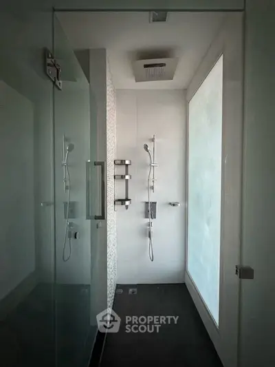 Modern minimalist bathroom with glass shower enclosure and sleek fixtures.