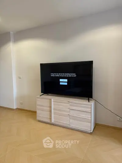 Modern living room with sleek TV and stylish wooden cabinet on elegant flooring.