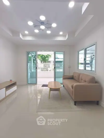Spacious living room with modern furniture and large windows opening to a balcony.