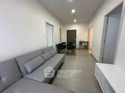 Modern living room with sleek gray sofa and dining area in contemporary apartment.