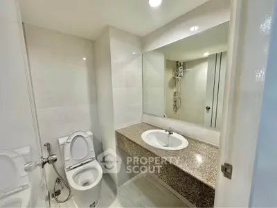 Modern bathroom with sleek design and spacious layout, featuring a large mirror and elegant fixtures.