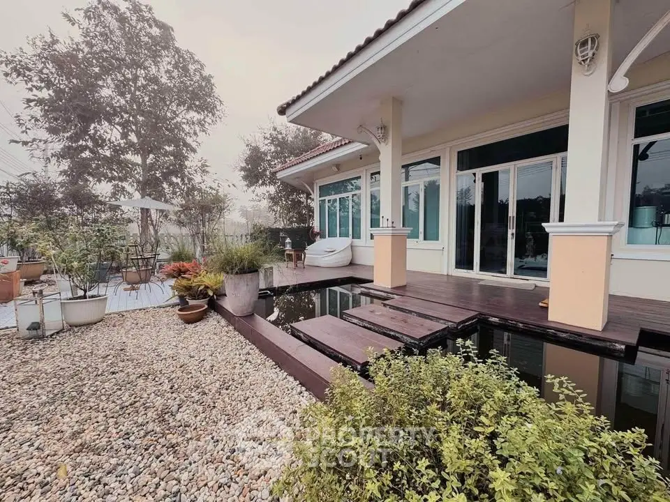 Charming house with serene garden and wooden deck overlooking a tranquil pond.