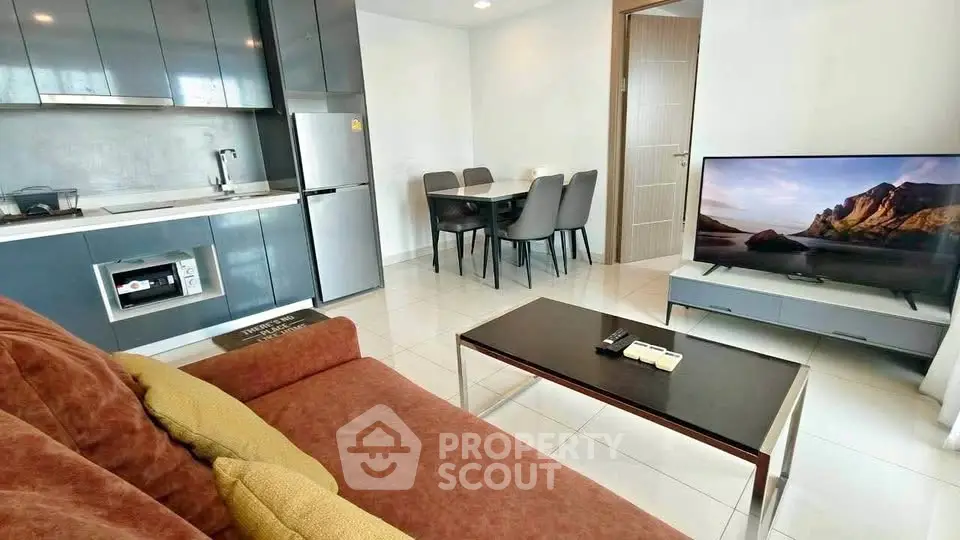 Modern living room with sleek kitchen, cozy sofa, and flat-screen TV in stylish apartment.