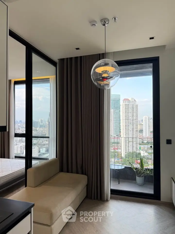 Modern apartment with floor-to-ceiling windows and city view from balcony, featuring stylish lighting and cozy seating.