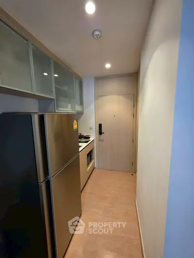 Modern compact kitchen with stainless steel fridge and sleek cabinetry