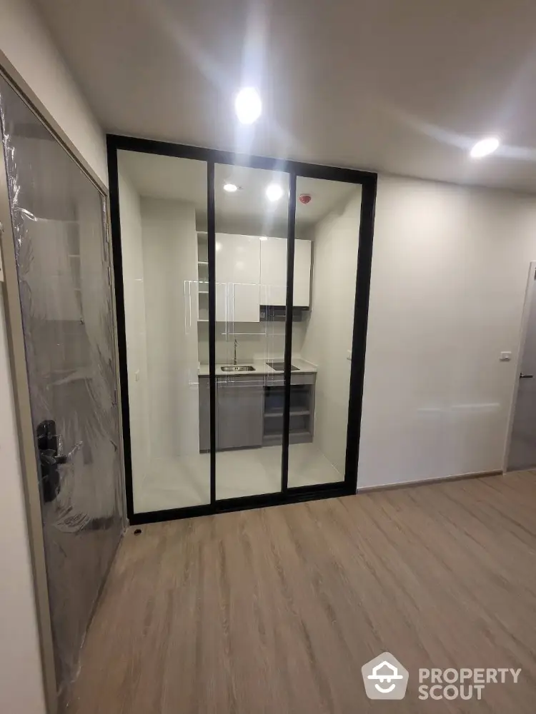 Modern compact kitchen with glass partition and sleek cabinetry