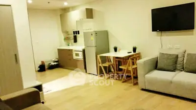 Modern open-plan living room with kitchen and dining area, featuring sleek furniture and appliances.