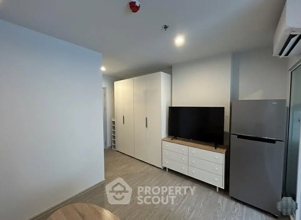 Modern living room with sleek furniture and appliances, featuring a TV and refrigerator for a comfortable lifestyle.
