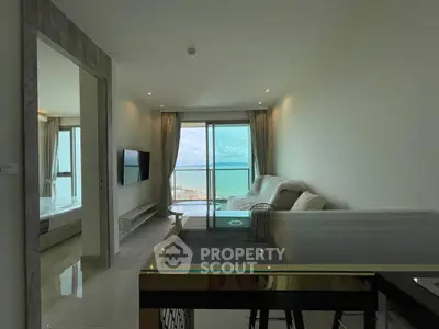 Modern living room with ocean view, open layout, and sleek furnishings in a high-rise apartment.