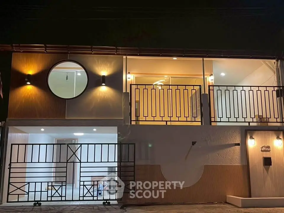 Modern two-story house with stylish balcony and unique circular window design.