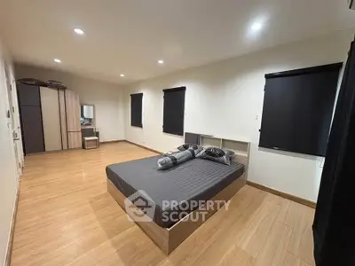 Spacious modern bedroom with sleek wooden flooring and stylish furnishings.