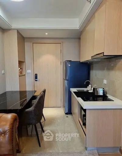 Modern kitchen with sleek cabinetry and dining area in stylish apartment.