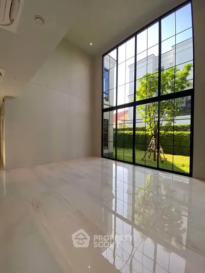 Spacious modern living room with large windows and garden view, perfect for natural light lovers.