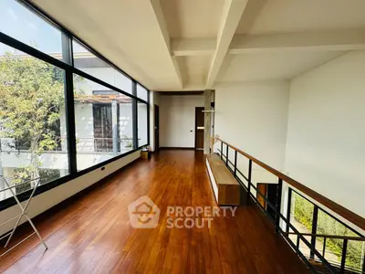 Spacious living area with polished hardwood floors and expansive windows offering abundant natural light and serene views, perfect for modern living.