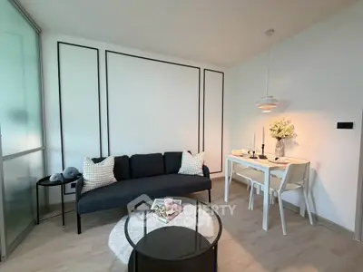 Modern living room with sleek black sofa, stylish dining area, and contemporary decor.