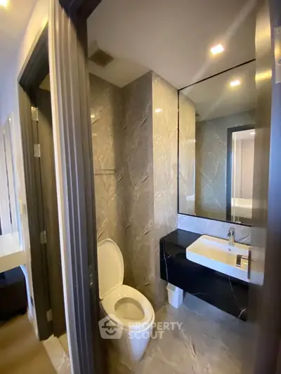 Modern bathroom with sleek design, featuring a stylish sink and elegant marble walls.