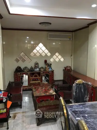 Elegant living room with traditional Asian decor and air conditioning, featuring ornate furniture and decorative pieces.