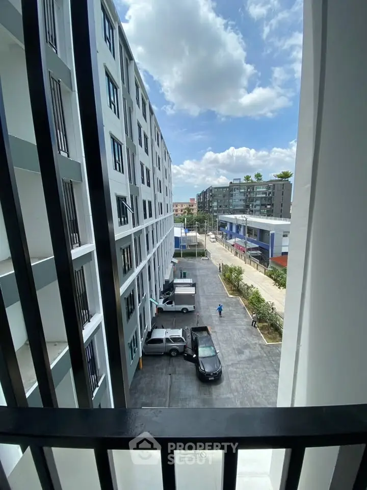 Modern apartment building with parking area and city view under a clear blue sky.