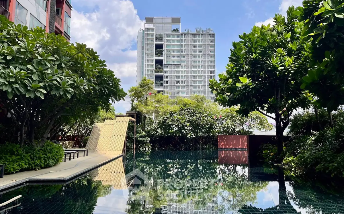 Luxurious residential building with serene pool and lush greenery, perfect for urban living.