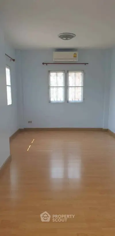 Spacious empty room with wooden flooring and natural light