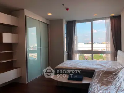 Modern bedroom with large window and city view, featuring sleek built-in shelves and stylish decor.
