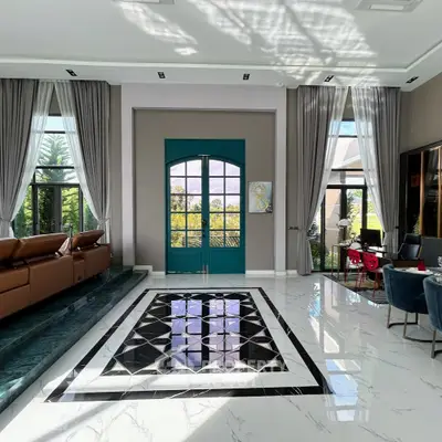 Luxurious living room with high ceilings, elegant marble flooring, and large windows offering natural light.