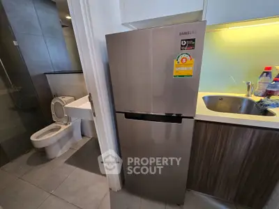 Compact kitchen with stainless steel fridge next to modern bathroom