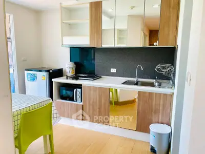 Modern kitchen with wood cabinets, dining table, and appliances in a cozy apartment.