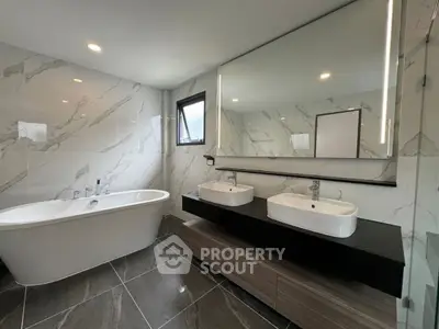 Luxurious modern bathroom with dual sinks and freestanding bathtub, featuring elegant marble tiles.