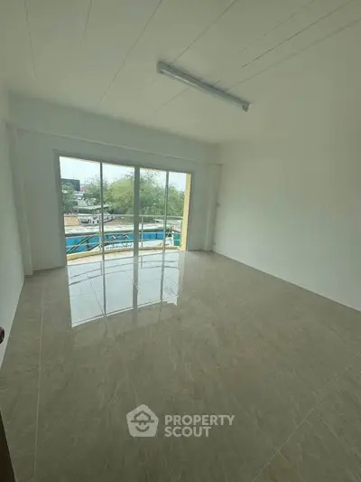 Spacious unfurnished room with large windows and tiled flooring, offering a bright and airy atmosphere.
