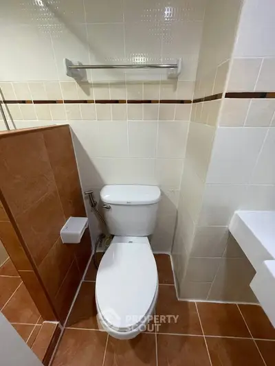 Compact bathroom with modern toilet and tiled walls, ideal for efficient space utilization.